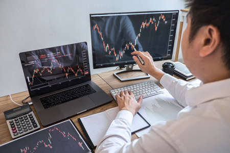 Stock exchange market concept, Business investor trading or stock brokers having a planning and analyzing with display screen and pointing on the data presented and deal on a stock exchange.の写真素材