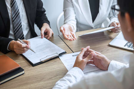 Employer or committee holding reading a resume with talking during about his profile of candidate, employer in suit is conducting a job interview, manager resource employment and recruitment concept.の写真素材