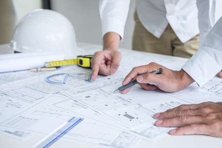 Team of engineering or architect meeting and discussing on blueprint and building model while checking information on sketching for architectural project.の写真素材