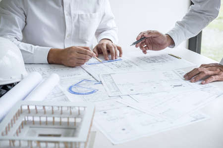Team of engineering or architect meeting and discussing on blueprint and building model while checking information on sketching for architectural project.の写真素材