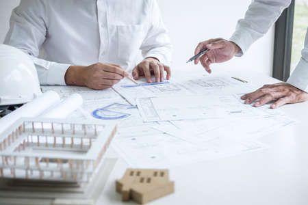 Team of engineering or architect meeting and discussing on blueprint and building model while checking information on sketching for architectural project.の写真素材