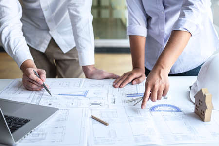 Team of construction engineering or architect partner discuss a blueprint while checking information on drawing and sketching meeting for architectural project with engineering equipment tool.の写真素材