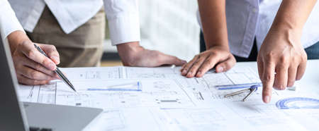 Team of engineering or architect meeting and discussing on blueprint and building model while checking information on sketching for architectural project.の写真素材