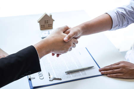 Finishing to successful deal of real estate, Broker and client shaking hands after signing contract approved application form, concerning mortgage loan offer for and house insurance.の写真素材