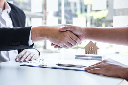 Finishing to successful deal of real estate, Broker and client shaking hands after signing contract approved application form, concerning mortgage loan offer for and house insurance.の写真素材