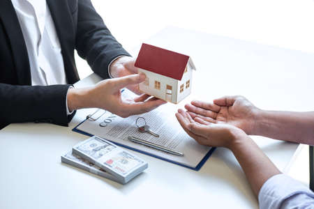 Estate agent giving house and keys to client after signing agreement contract real estate with approved mortgage application form, concerning mortgage loan offer for and house insurance.の写真素材
