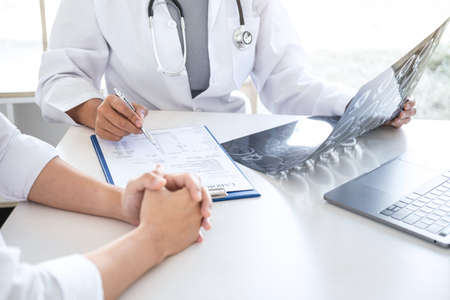 Professor Doctor having conversation with patient and holding x-ray film while discussing explaining symptoms or counsel diagnosis health, healthcare and assistance concept.の写真素材