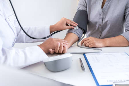 Doctor using a measuring blood pressure checking patient with examining, presenting results symptom and recommend treatment method, Healthcare and medical concept.の写真素材