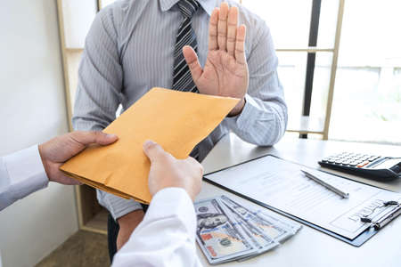 Anti bribery and corruption concept, Business man refusing and don't receive money banknote in envelope offer from business people to accept agreement contract of investment deal.の写真素材