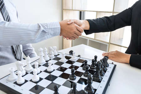 Businessman and businesswoman shaking hands after playing chess and thinking about strategy crash overthrow the opposite team and development analysis for win and successful.の写真素材