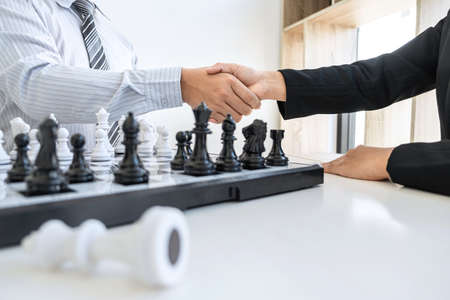 Businessman and businesswoman shaking hands after playing chess and thinking about strategy crash overthrow the opposite team and development analysis for win and successful.の写真素材