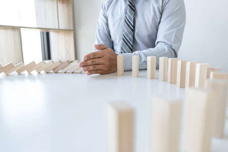 Risk and Strategy in Business, Image of hand stopping falling collapse wooden block dominoes effect from continuous toppled block, prevention and development to stability.の写真素材