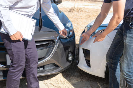 Insurance agent examine the damage of the car after accident on report claim form process.の写真素材