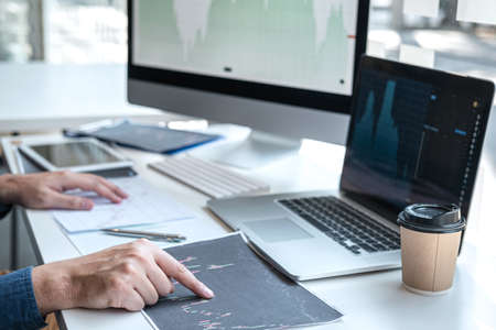 Stock exchange market concept, stock broker looking at graph working and analyzing with display screen, pointing on the data presented and deal on a exchange, Businessman trading stocks online.の写真素材