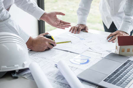 Team of engineering or architect meeting and discussing on blueprint and building model while checking information on sketching for architectural project.の写真素材