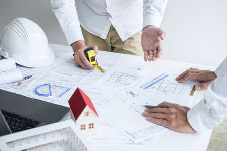Construction engineering or architect discussing a blueprint and building model while checking information on sketching meeting for architectural project in work site.の写真素材