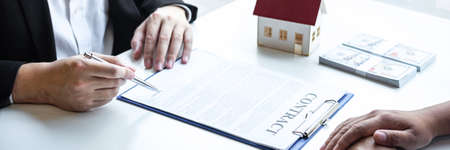 Estate agent broker reach contract form and presentation to client signing agreement contract real estate with approved mortgage application form, buying mortgage loan offer for and house insurance.の写真素材