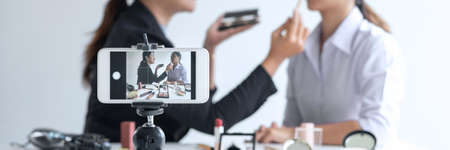 Business online on social media, Two Beautiful Woman Blogger is showing present tutorial beauty cosmetic product and broadcast live streaming video to social network while recording teaching online.の写真素材