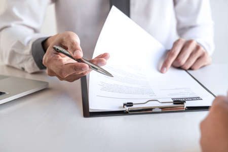 Employer or recruiter holding reading a resume during about colloquy his profile of candidate, employer in suit is conducting a job interview, manager resource employment and recruitment concept.の写真素材