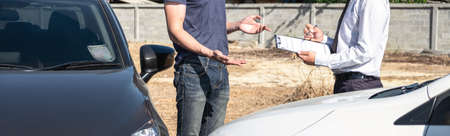 Insurance agent examine the damage of the car after accident on report claim form process.の写真素材