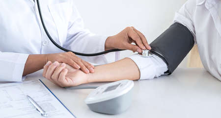 Doctor using a measuring blood pressure checking patient with examining, presenting results symptom and recommend treatment method, Healthcare and medical concept.の写真素材