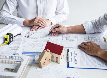 Construction engineering or architect discussing a blueprint and building model while checking information on sketching meeting for architectural project in work site.の写真素材