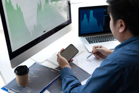 Stock exchange market concept, stock broker looking at graph working and analyzing with display screen, pointing on the data presented and deal on a exchange, Businessman trading stocks online.の写真素材