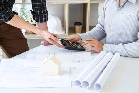 Construction engineering or architect discussing a blueprint and building model while checking information on sketching meeting for architectural project in work site.の写真素材
