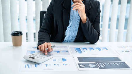 Business woman are the numeric data from the chart using a calculator, investment chart using the calculator on the desk in her office working by reviewingの写真素材