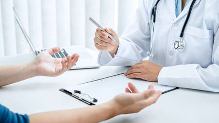 Doctor hold pen and patient discussing something in medical clinic, doctor talk about medicine ,health care concept and writing a prescriptionの写真素材