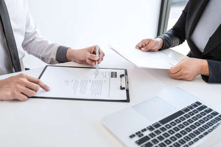 Employer or recruiter holding reading a resume during about colloquy his profile of candidate, employer in suit is conducting a job interview, manager resource employment and recruitment concept.の写真素材