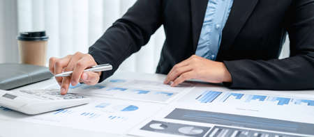 Business woman are the numeric data from the chart using a calculator, investment chart using the calculator on the desk in her office working by reviewingの写真素材