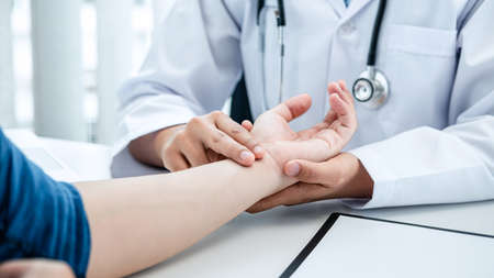The doctor hold the patient on the wrist to take the pulse heart rate, the doctor work at the clinic explain about treatment, health care and writhing a prescription medicine to patientの写真素材