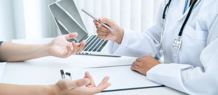 Doctor hold pen and patient discussing something in medical clinic, doctor talk about medicine ,health care concept and writing a prescriptionの写真素材