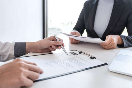 Employer or recruiter holding reading a resume during about colloquy his profile of candidate, employer in suit is conducting a job interview, manager resource employment and recruitment concept.の写真素材