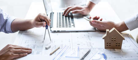 Team of engineering or architect meeting and discussing on blueprint and building model while checking information on sketching for architectural project.の写真素材