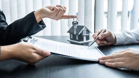 Estate agent giving house and keys to client after signing agreement contract real estate with approved mortgage application form for or house insurance.の写真素材