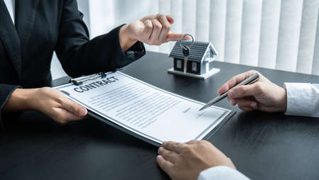Estate agent giving house and keys to client after signing agreement contract real estate with approved mortgage application form for or house insurance.の写真素材
