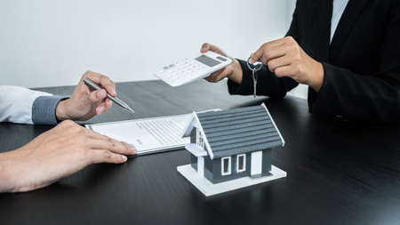 Estate agent giving house and keys to client after signing agreement contract real estate with approved mortgage application form for or house insurance.の写真素材