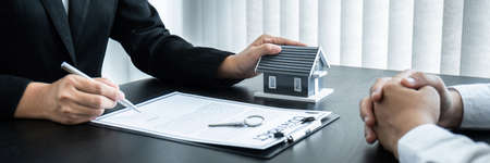 Estate agent giving house and keys to client after signing agreement contract real estate with approved mortgage application form for or house insurance.の写真素材