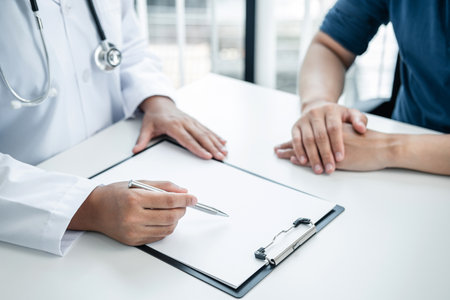 Doctor is explaining the symptoms to the patient at medical clinic, doctor is reading the details of the treatment health care and writing prescriptions to the patientの写真素材