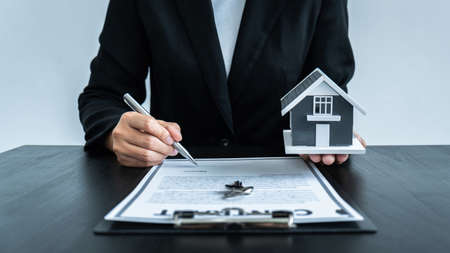 Estate agent giving house and keys to client after signing agreement contract real estate with approved mortgage application form for or house insurance.の写真素材