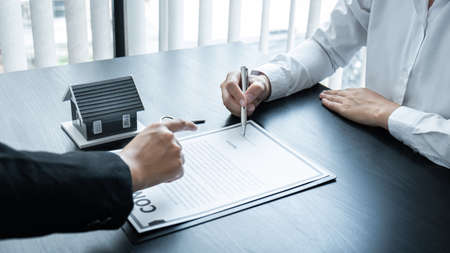 Estate agent broker presentating to client decision signing agreement contract real estate with approved mortgage application, buying mortgage loan offer for and house insurance.の写真素材
