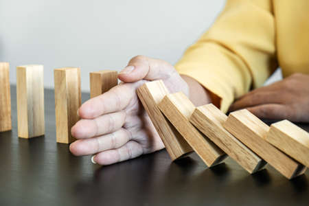 Risk and Strategy in Business, Image of hand stopping falling collapse wooden block dominoes effect from continuous toppled block, prevention and development to stability.の写真素材