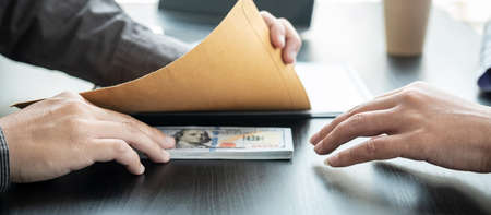 Man employee put bribe money under envelope given to businessman after signing on the contract to joint engage in illegal and immoral projectの写真素材