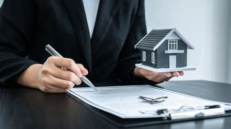 Estate agent giving house and keys to client after signing agreement contract real estate with approved mortgage application form for or house insurance.の写真素材