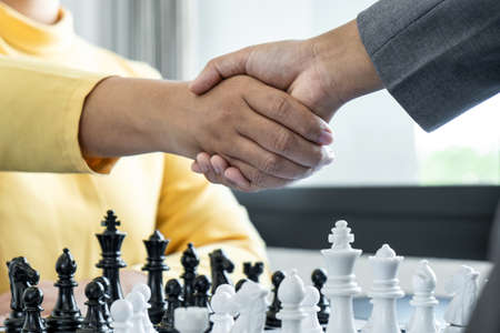 Businessman shaking hands after playing chess and thinking about strategy crash overthrow the opposite team and development analysis for win and successful.の写真素材