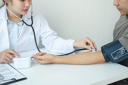 Doctor is checking blood pressure for the patient and using stethoscope to listening heartbeat while diagnosing disease and illness symptoms of patient at her clinicの写真素材