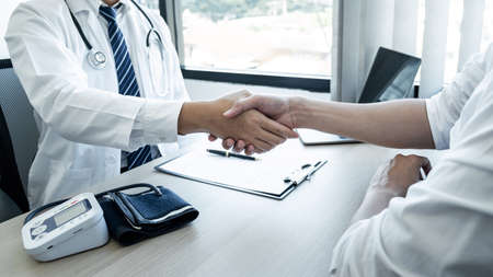 Doctor having shaking hands to congrats with patient after recommend sickness treatment while discussing explaining his symptoms and counsel diagnosis health, healthcare and assistance concept.の写真素材