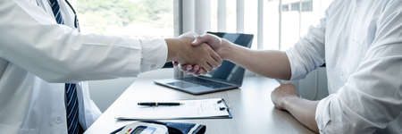 Doctor having shaking hands to congrats with patient after recommend sickness treatment while discussing explaining his symptoms and counsel diagnosis health, healthcare and assistance concept.の写真素材